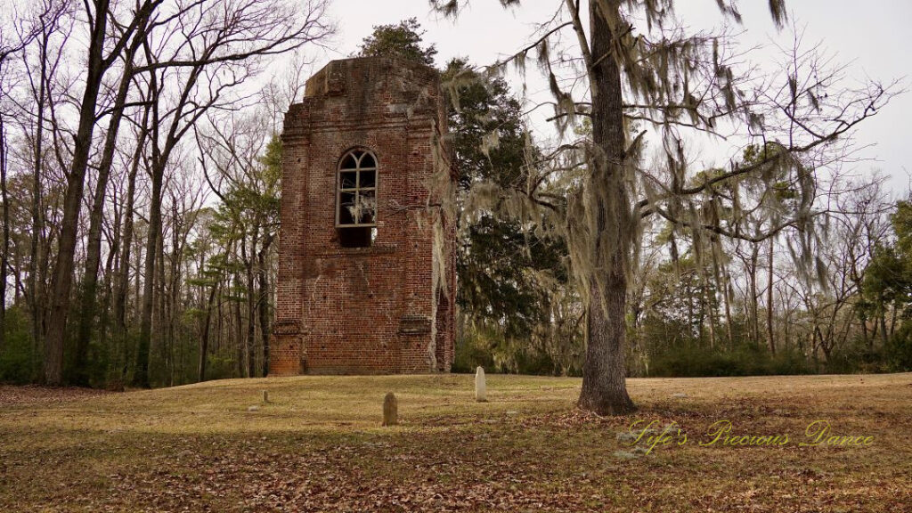 Bell tower ruins at Colonial Dorchester State Historic Site, Three tombstones and a tree covered in spanish moss in the foreground.