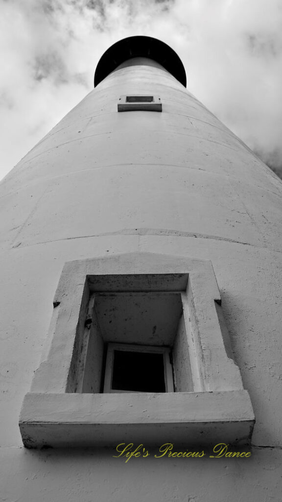 Black and white upwards view of the Hunting Island lighthouse. Clouds up above.