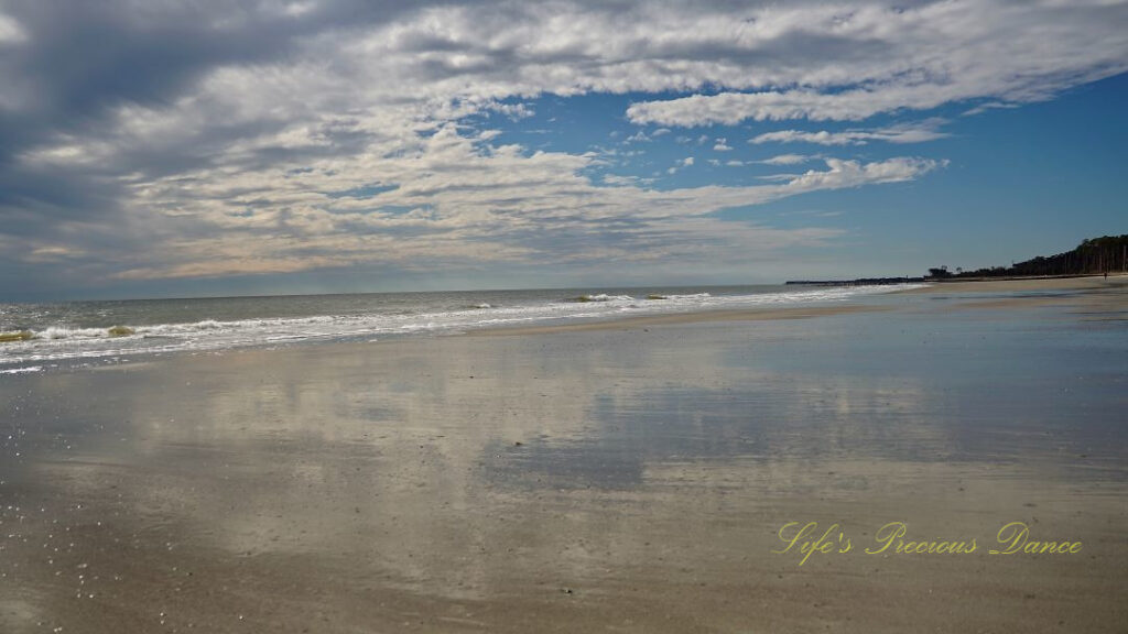 Seascape view of the ocean, Waves rolling in and blue skies and clouds reflecting on the beach.