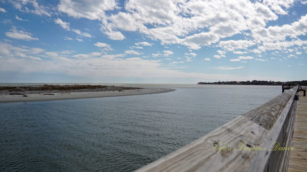 View from a pier overlooking the atlantic ocean at Hunting Island State Park. Fluffy clouds overhead.