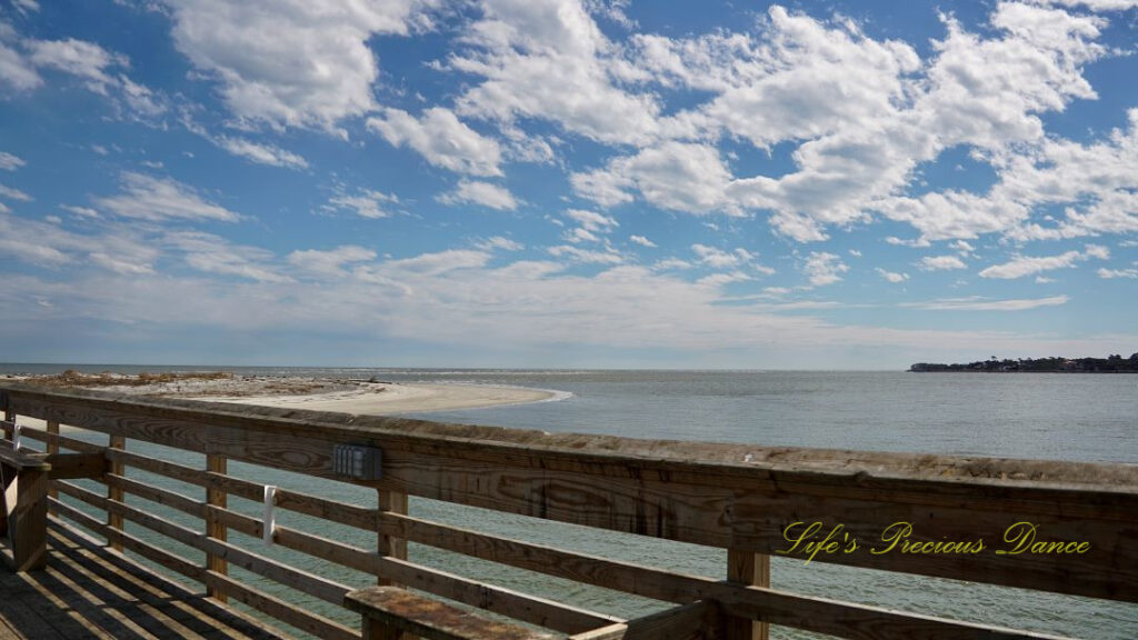 View from a pier overlooking the atlantic ocean at Hunting Island State Park. Fluffy clouds overhead.