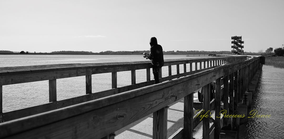 Black and white of a fisherman on a pier at Sands Beach.