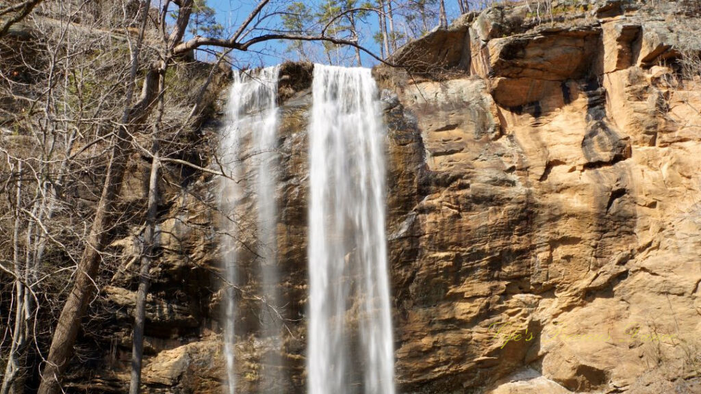 An 186 foot waterfall spilling over a rock face into a pool of water at Toccoa Falls.