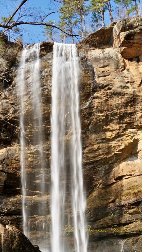 An 186 foot waterfall spilling over a rock face into a pool of water at Toccoa Falls.