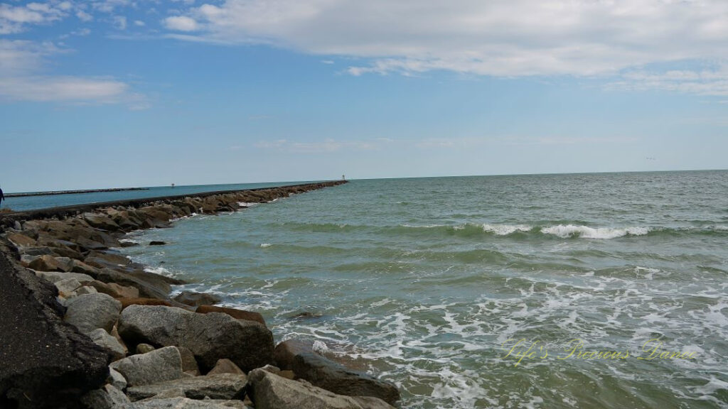 Long view of the jetty curving around the ocean at Huntington Beach.