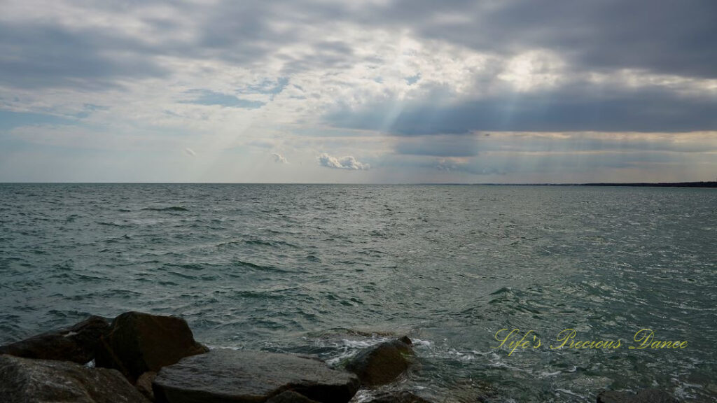 View of the atlantic ocean from the jetty at Huntington Beach. The sun&#039;s rays can be seen through the clouds.