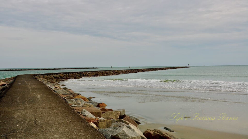 Long view of the jetty curving around the ocean at Huntington Beach.