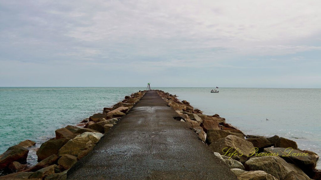 End of the jetty at Huntington Beach surrounded on three sides by the atlantic ocean. A fishing boat to the right,