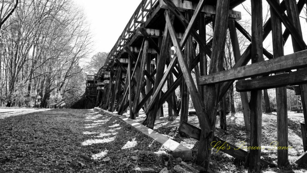 Black and white underside view of an old train trestle.