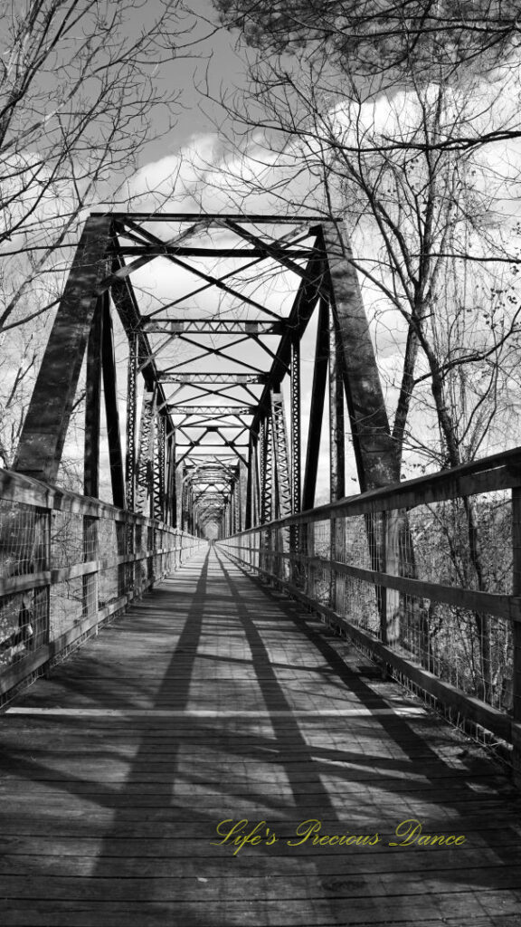 Black and white straight on view of an old train trestle turned walking bridge.