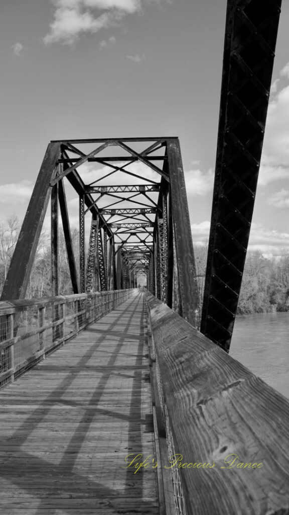 Black and white straight on view of an old train trestle turned walking bridge.