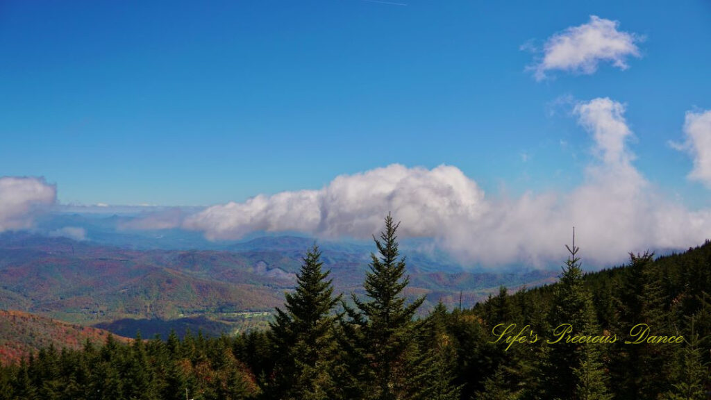 Landscape view from the top of Mt Mitchell overlooking colorful mountain peaks and trees in the valley. Passing clouds above.