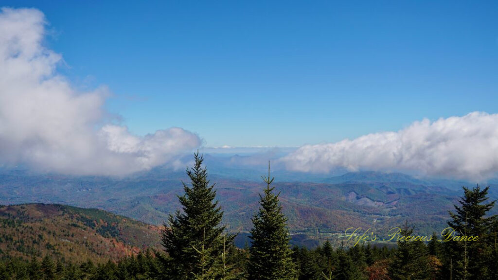 Landscape view from the top of Mt Mitchell overlooking colorful mountain peaks and trees in the valley. Passing clouds above.