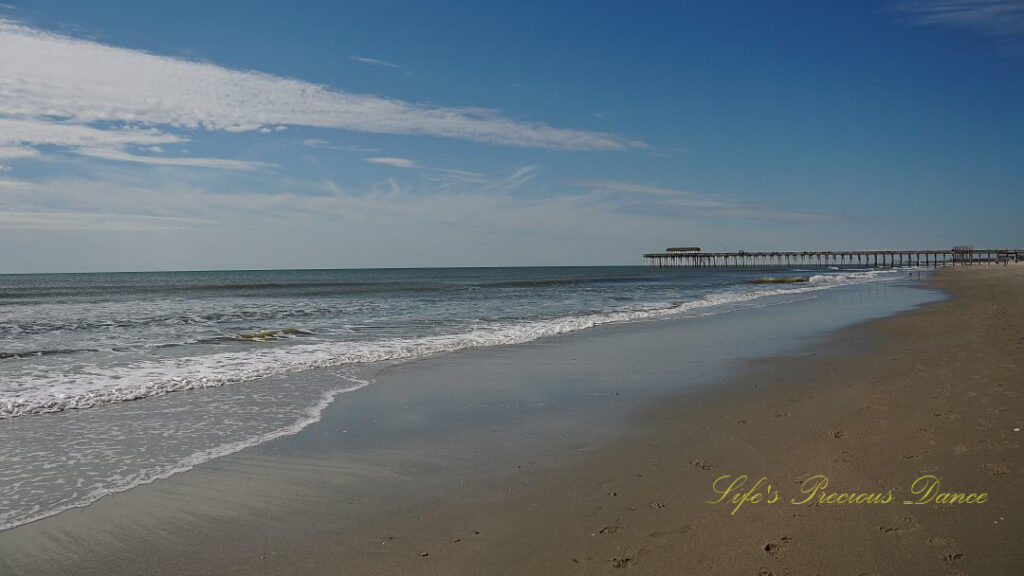 Waves crashing into the beach. The Myrtle Beach pier in the background.