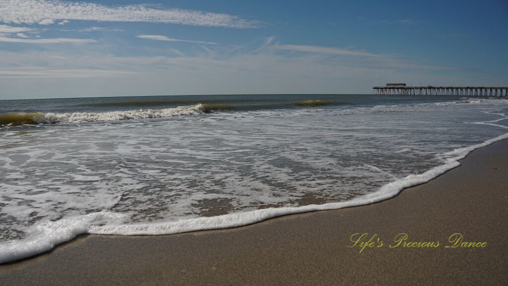 Waves crashing into the beach. The Myrtle Beach pier in the background.