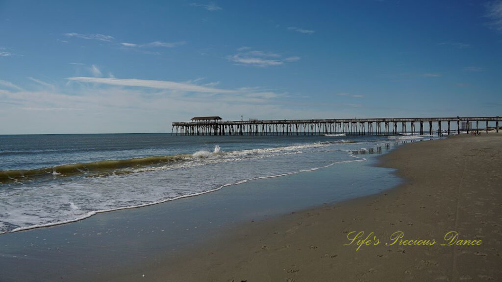 The Myrtle Beach pier stretching out into the atlantic ocean as waves roll in.