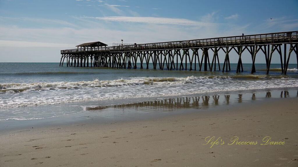 Side view of the Myrtle Beach pier. Clouds overhead and waves rolling in.