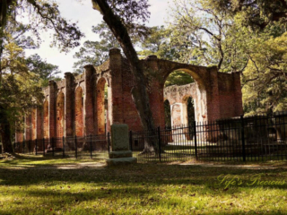 Rear side view of the Old Sheldon Church ruins. An old tombstone stands to the side.