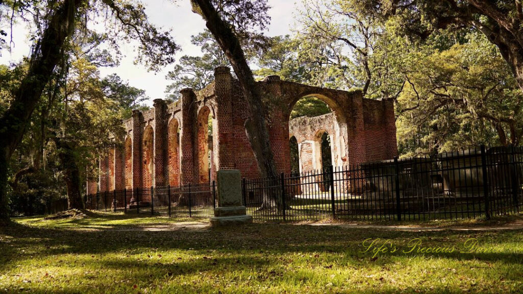 Rear side view of the Old Sheldon Church ruins. An old tombstone stands to the side.