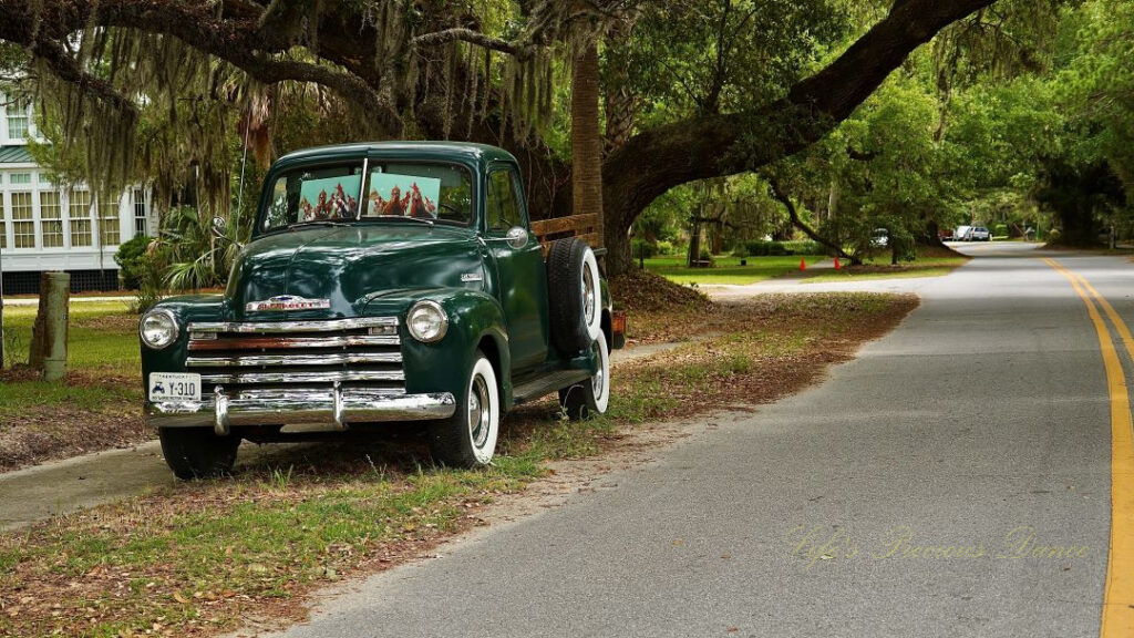 Front and side view of a classic dark green 1953 chevrolet 3100 truck.