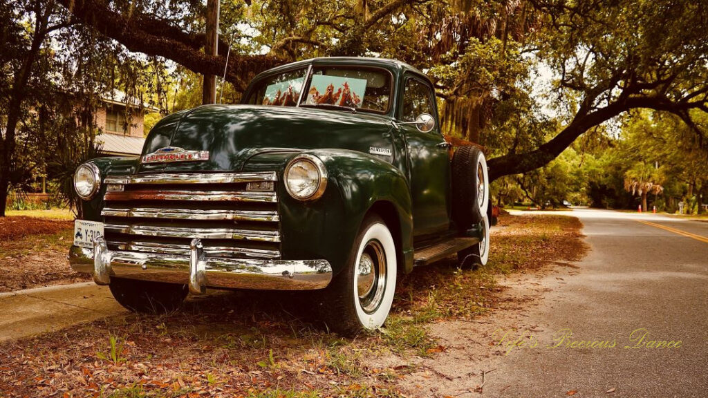 Close up front and side view of a classic dark green 1953 chevrolet 3100 truck.