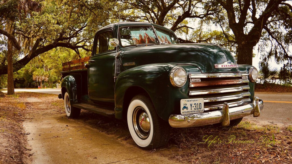 Close up front and side view of a classic dark green 1953 chevrolet 3100 truck.