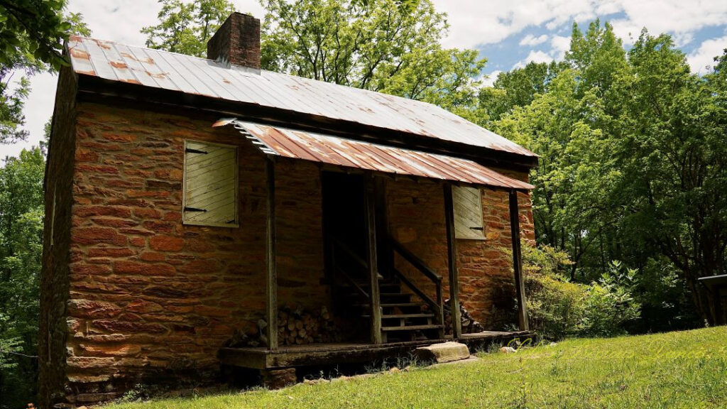 Front view of a stone blockhouse at Oconee Station State Historic Site. Trees in the background and clouds overhead.