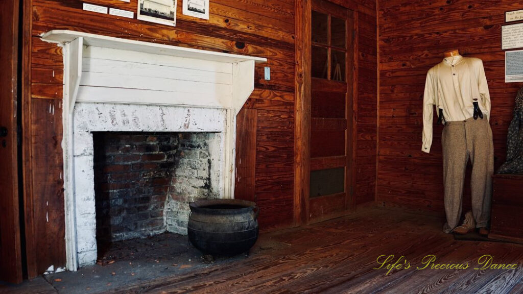 Inside of old servant quarters at Redcliffe Plantation. Fireplace to the left and a suit of clothes to the right,