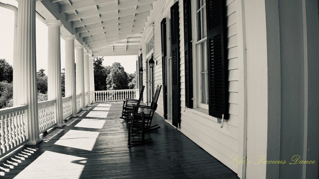 Black and white of rocking chairs sitting on the front porch of the Redcliffe Plantation mansion.