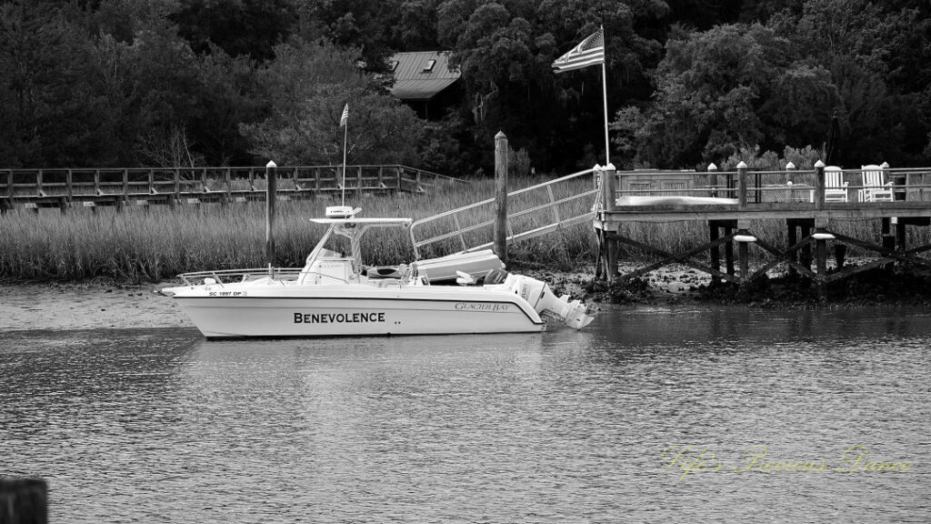 Black and white of a fishing boat tied to a dock at Jeremy Creek Landing. An American Flag stands above.