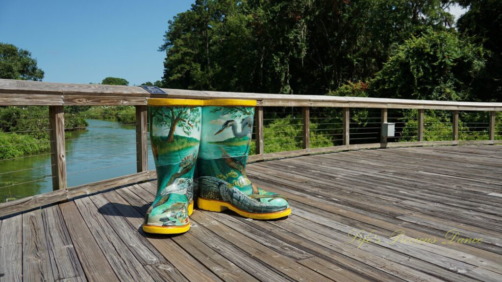 Boot sculptures, painted with the wildlife of the wetlands, on a deck overlooking the water.