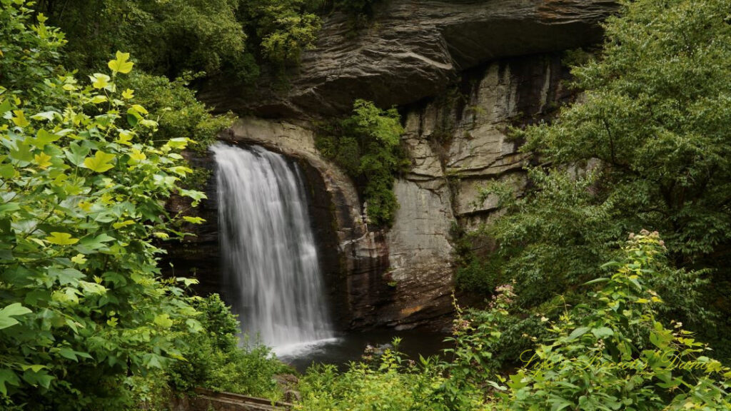 Looking Glass Falls pouring down a rockface into the awaiting mountain stream below.