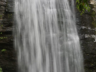 Looking Glass Falls pouring down a rockface into the awaiting mountain stream below.