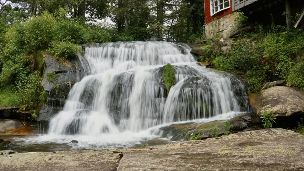 Mill Shoal Falls spilling over rocks into a pool of water. Rock slabs in the foreground.