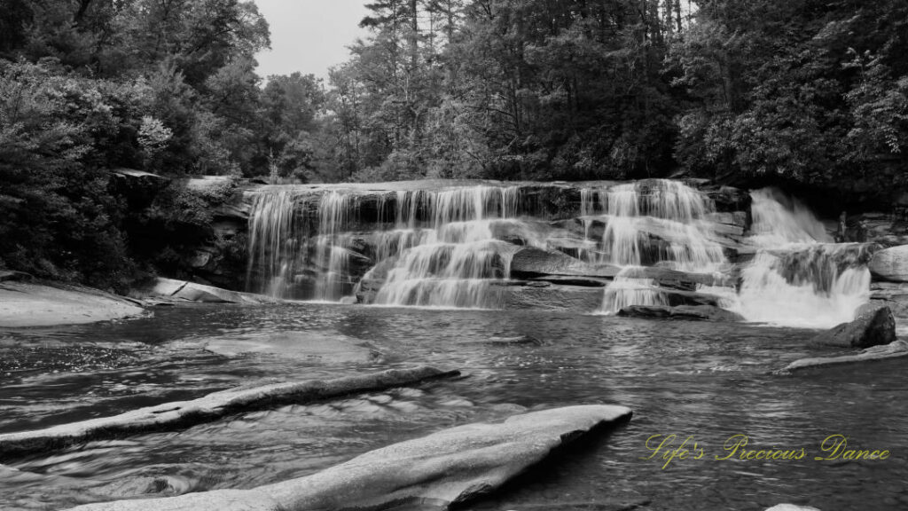 Black and white view of French Broad Falls spilling over a rockface into the river below.