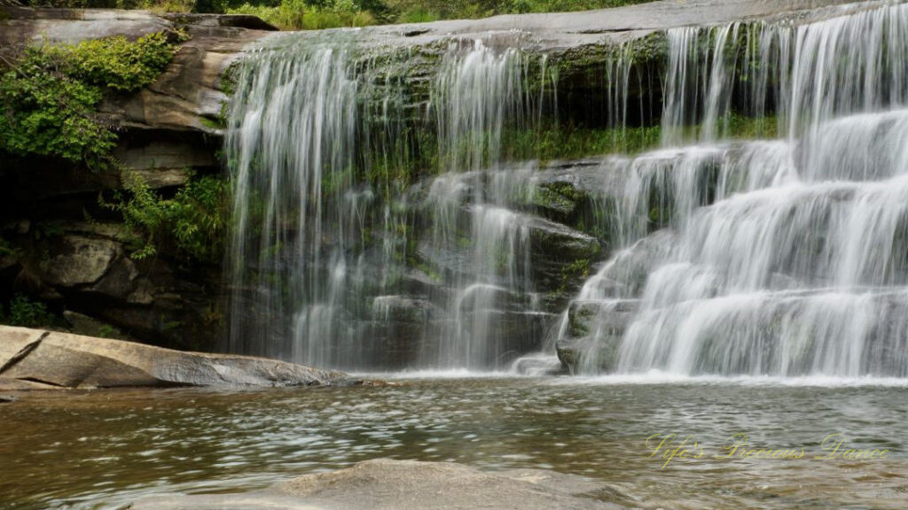 Close up of French Broad Falls spilling over a rockface into the river below.