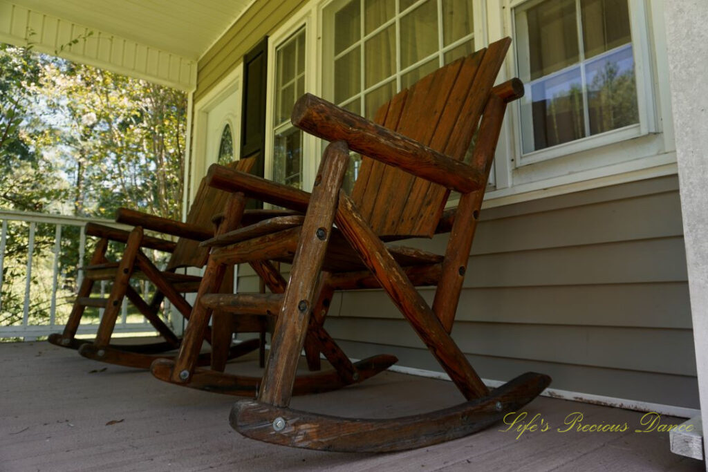 Looking upward at wooden rocking chairs on a porch.