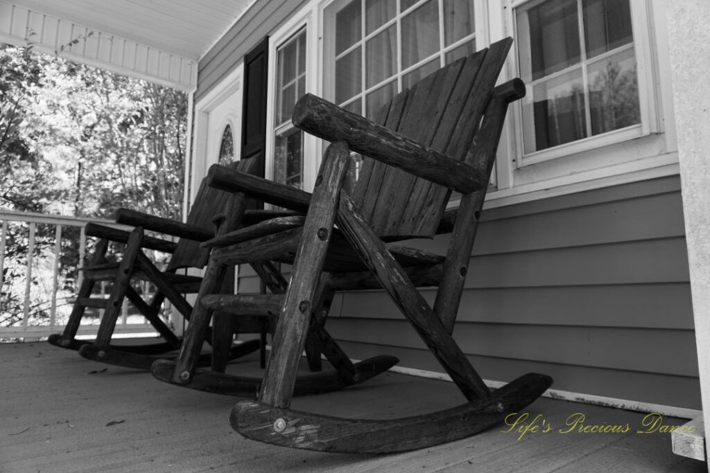 Looking upwards at wooden rocking chairs on a porch.