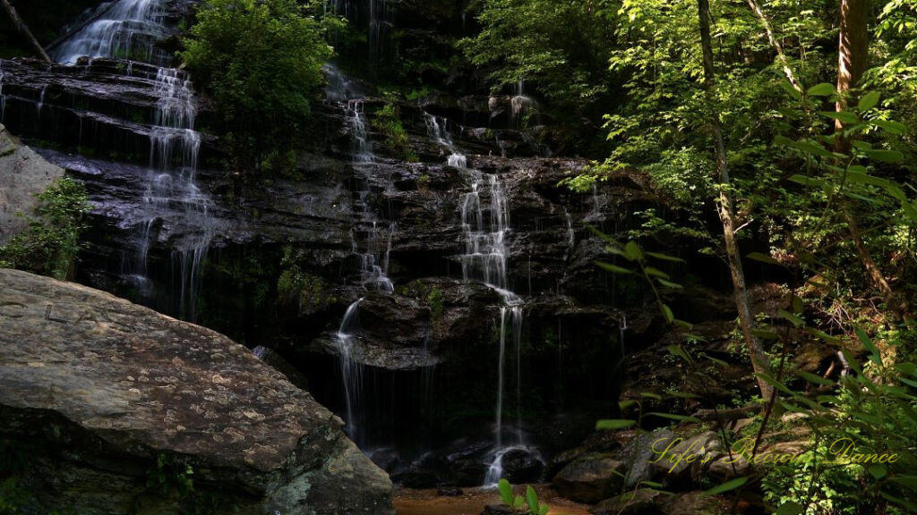 Lower section of Issaqueena Falls, spilling over the jagged rockface into a pool of water below.