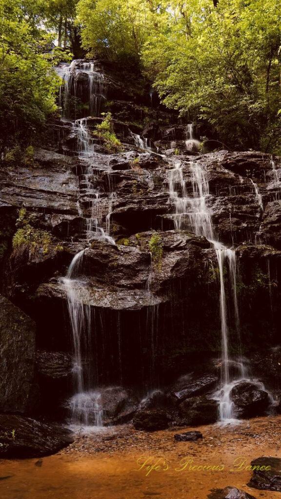 Issaqueena Falls spilling down the jagged rockface into a pool of water below.