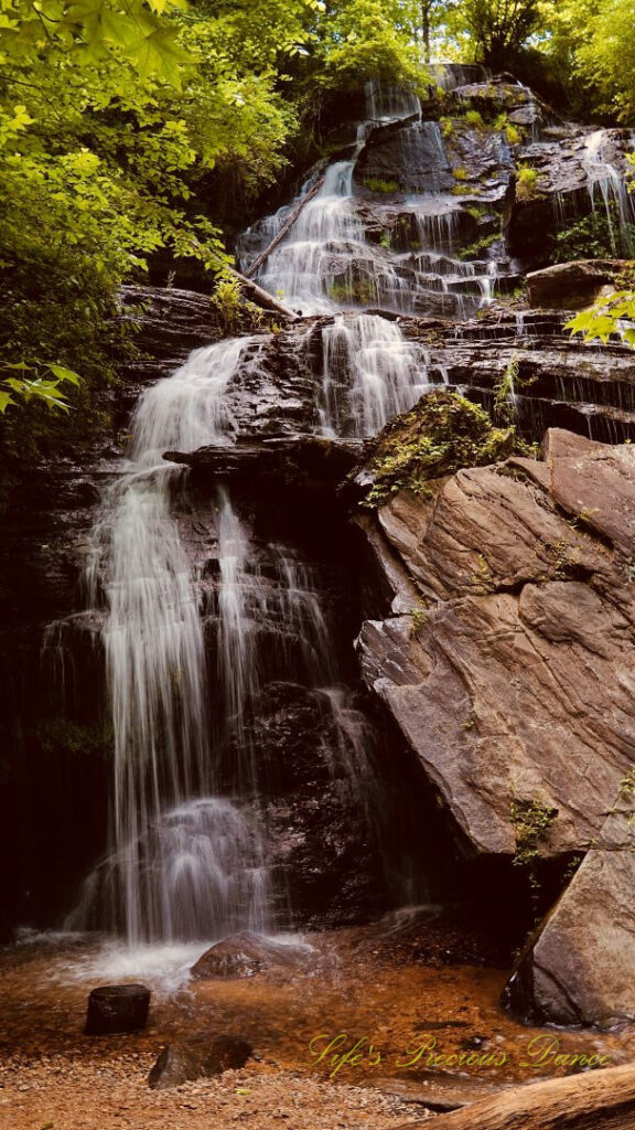 Issaqueena Falls spilling down the jagged rockface into a pool of water below.