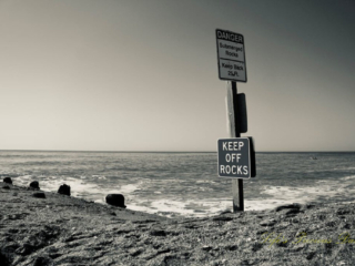 Black and white warning sign to Keep Off Rocks at Edisto Beach. A clam ocean in the background.