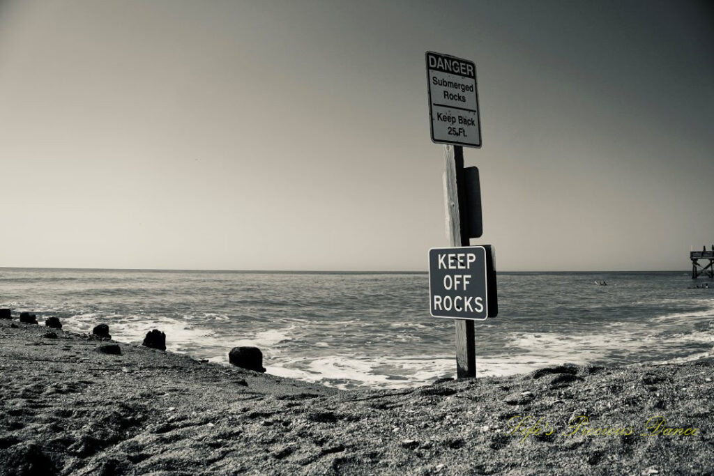 Black and white warning sign to Keep Off Rocks at Edisto Beach. A clam ocean in the background.