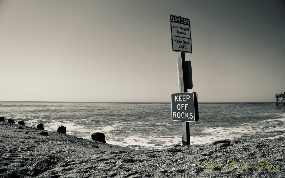 Black and white warning sign to Keep Off Rocks at Edisto Beach. A clam ocean in the background.