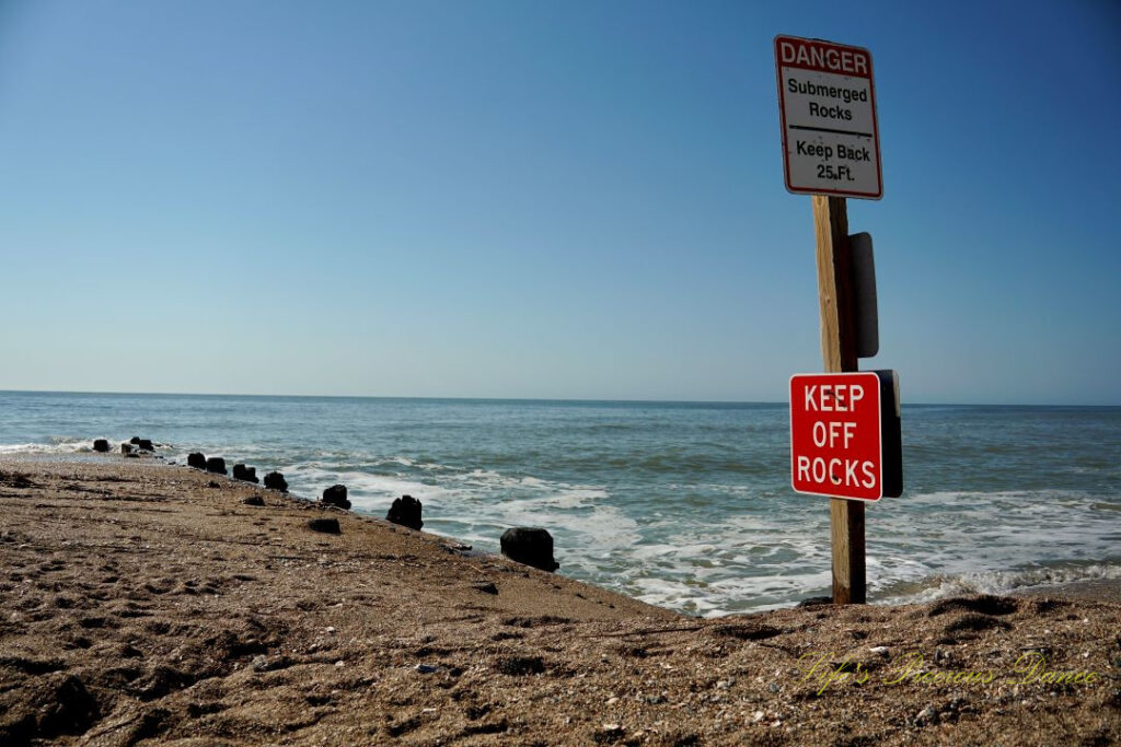 Warning sign to Keep Off Rocks at Edisto Beach State Park. Atlantic Ocean in the background.