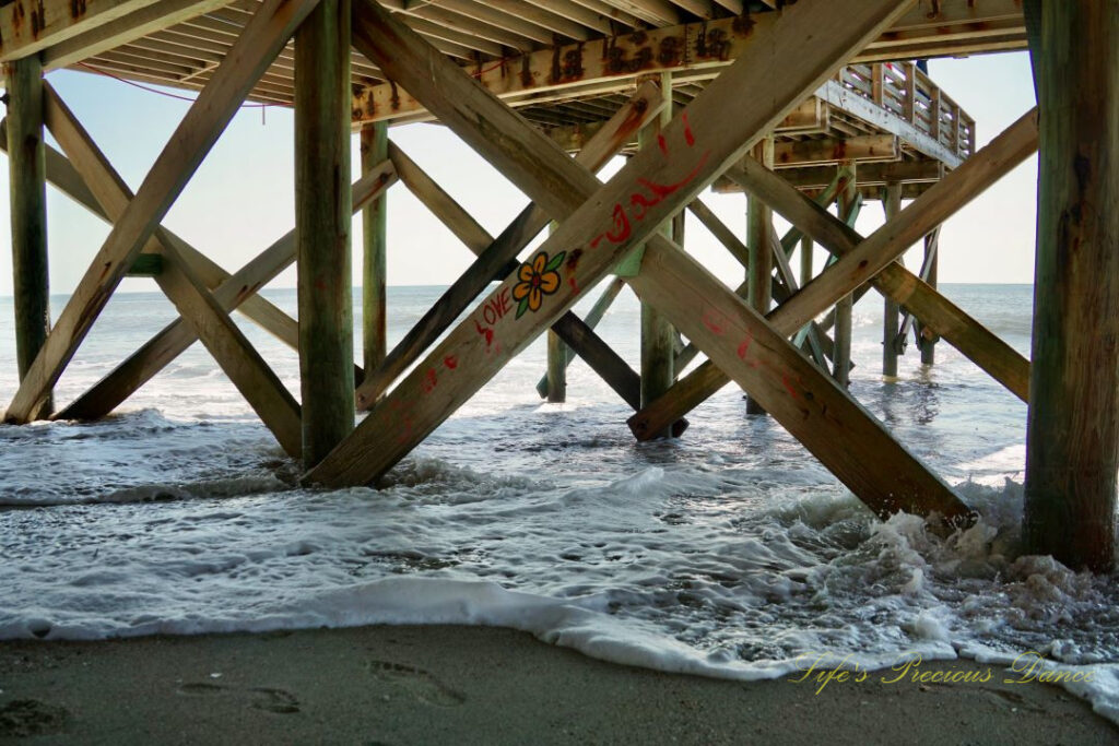 Underside view of the pier at Edisto Beach. Graffiti on a support beam with a flower and the word Love.