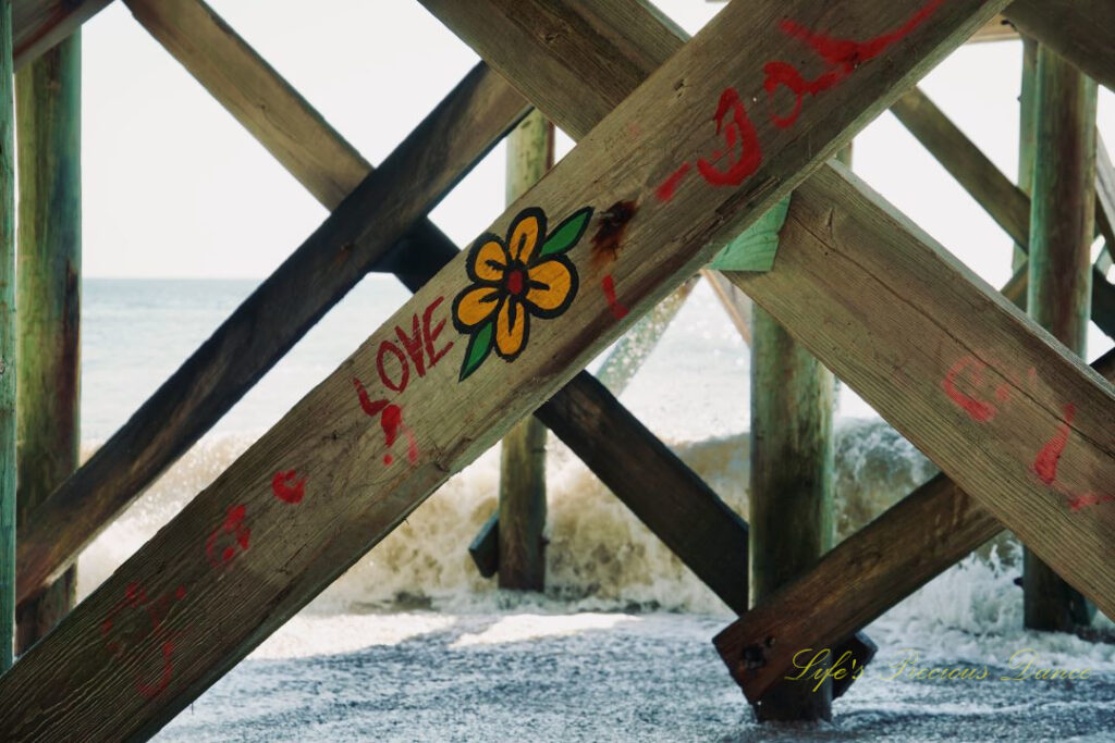 Close up of graffiti on the underside of the pier at Edisto Beach, stating the word Love and a colorful flower,