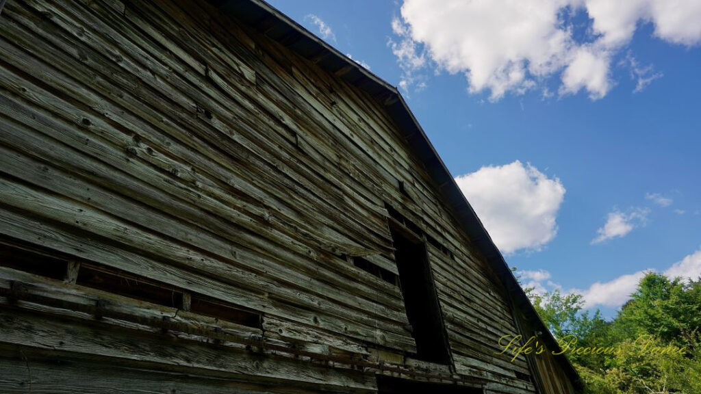 Close up of the upper portion of an old barn. Passing clouds overhead,