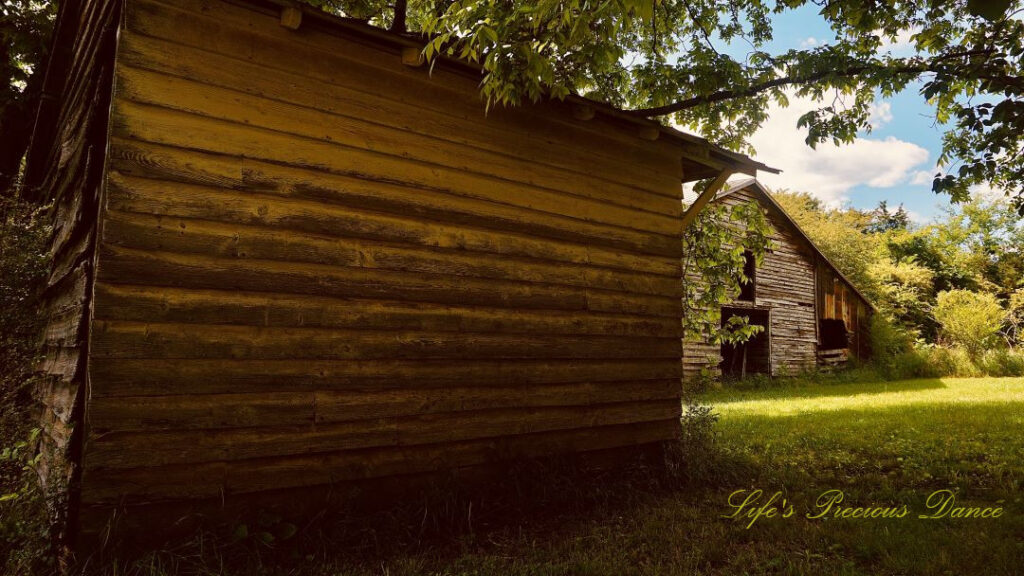 Side view of an out building at a farm. A barn in the background.