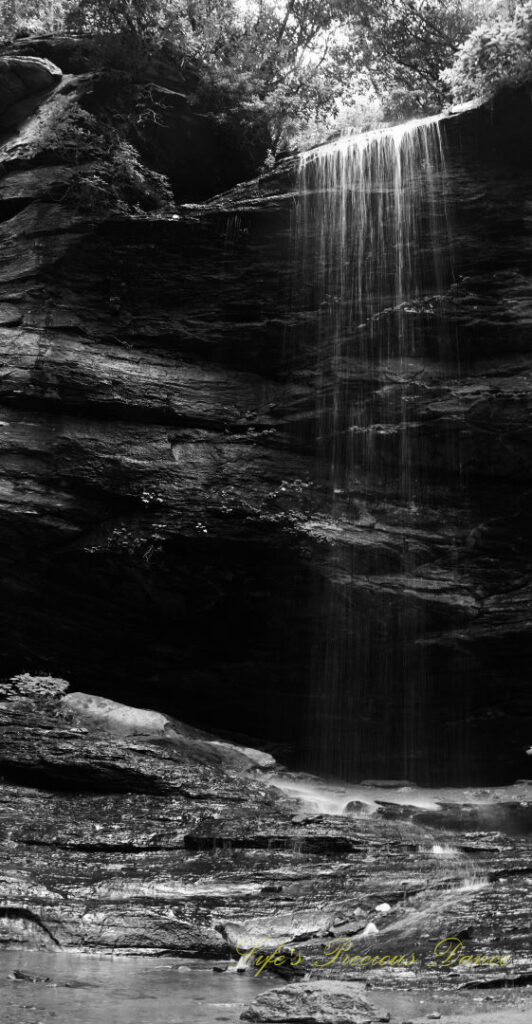 Black and white of Moore Cove Falls spilling over the rock ledge into a pool of water below.